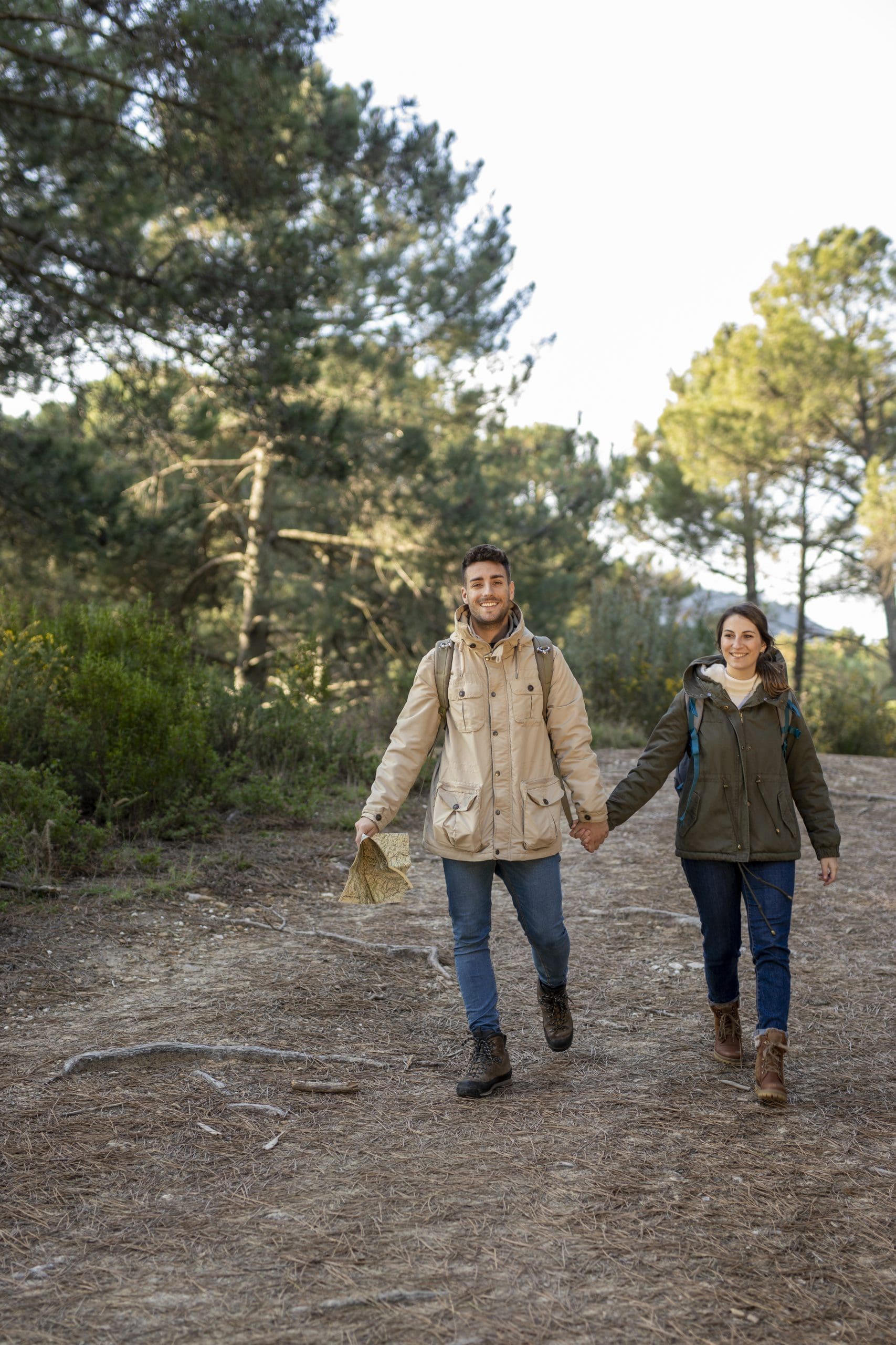 Una chica y un chico caminando por un sendero con muchos árboles alrededor