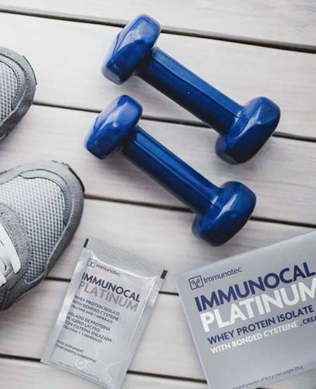 Unos tennis y unas pesas junto a una caja y un sobre de Immunocal Platinum