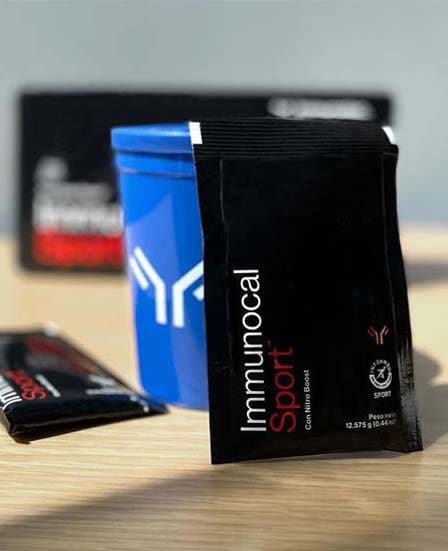 Un sobre de Immunocal Sport sostenido por un vaso mezclador de Immunotec