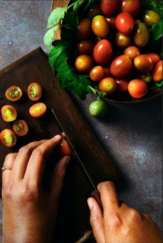 Unas manos cortando tomates pequeños