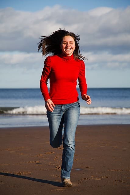 Chica corriendo feliz y descalza por la playa