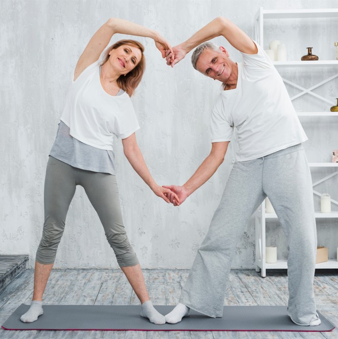 Dos personas adultas ejercitándose que se agarran las manos formando un corazón entre los dos