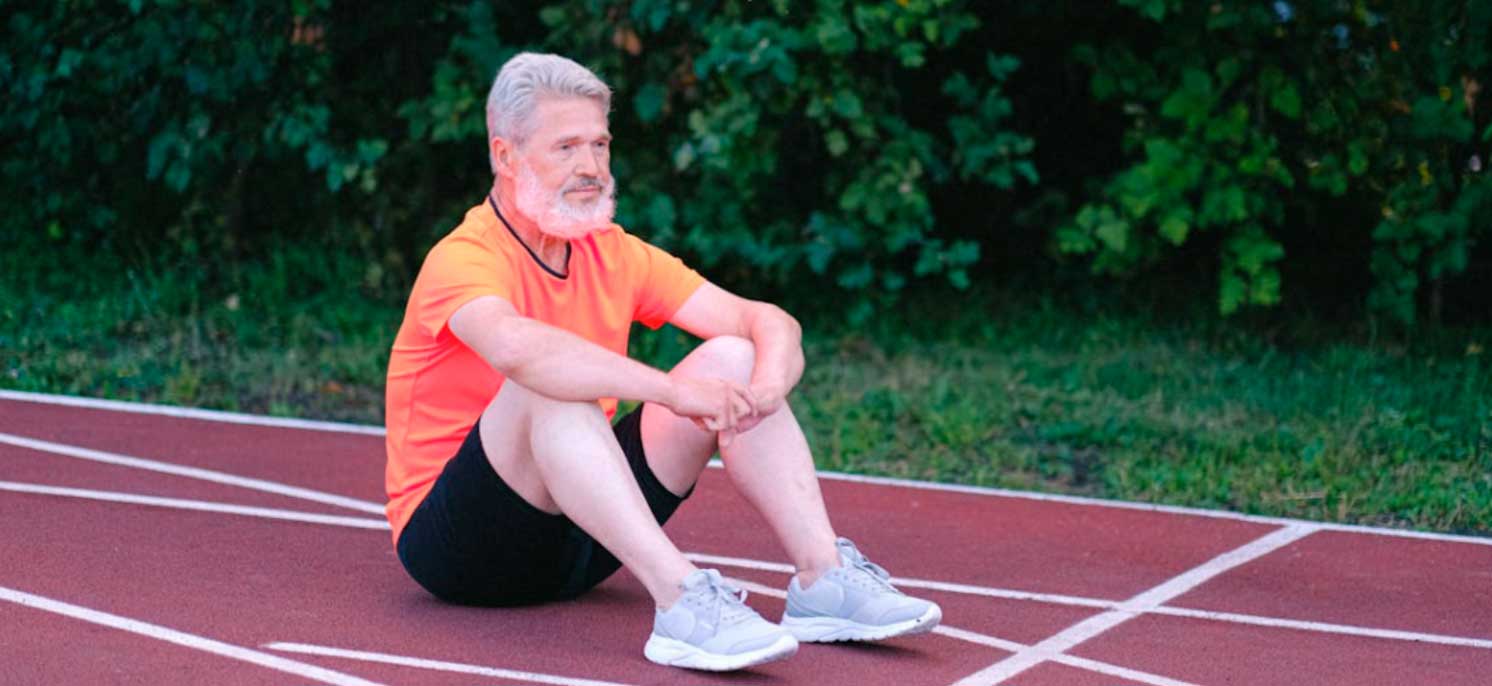 Hombre adulto sentado descansando en una pista de atletismo
